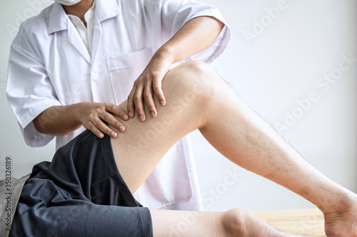 Doctor or Physiotherapist working examining treating injured leg of athlete male patient, Doing the Rehabilitation therapy pain in clinic