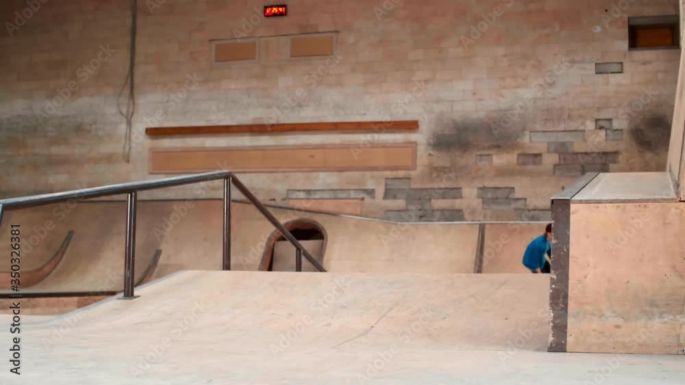 Wide shot of Caucasian skater boy wearing bright street-style clothes jumping on small ramp in skate park Wide shot of Caucasian skater boy wearing bright street-style clothes jumping on small ramp in skate park