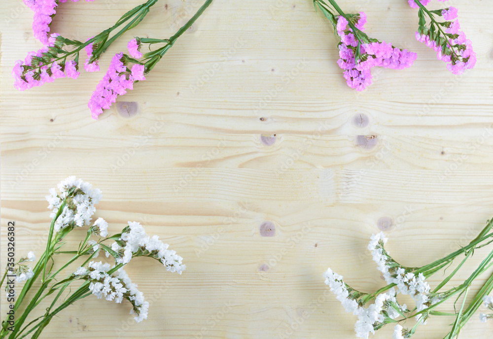Naklejka premium white and purple flowers on wooden background in aerial shot with copyspace