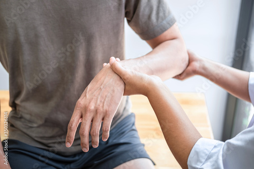 Female Physiotherapist working examining treating injured arm of athlete male patient, stretching and exercise, Doing the Rehabilitation therapy pain in clinic