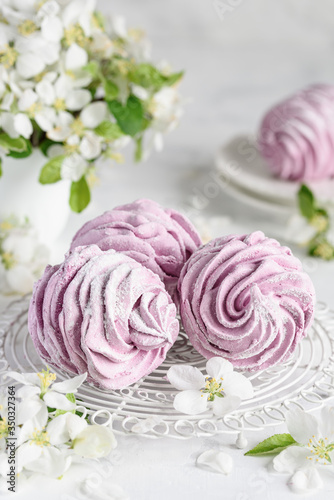 Homemade berry zephyr or russian marshmallows on a white stand with apple blossoms. Confectionery concept. Natural healthy dessert. Selective focus. © Olga Romankova
