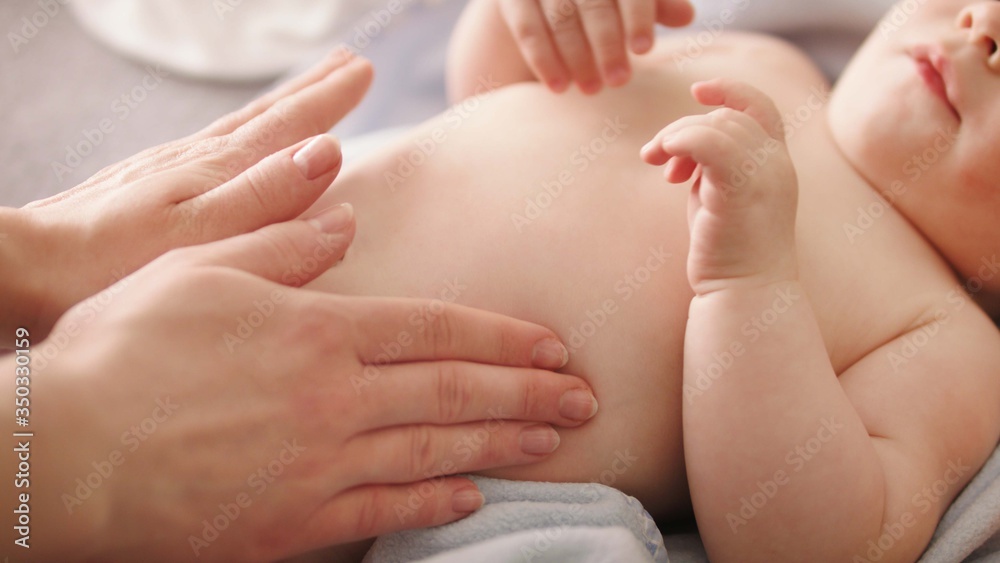 Mother massaging baby tummy. Baby skin care and development concept.