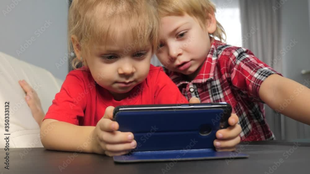 children watch online video on a smartphone. little boy and girl brother sister lifestyle watch online streaming broadcasting cartoons on the phone children watch online video on a smartphone. little boy and girl brother sister lifestyle watch online streaming broadcasting cartoons on the phone