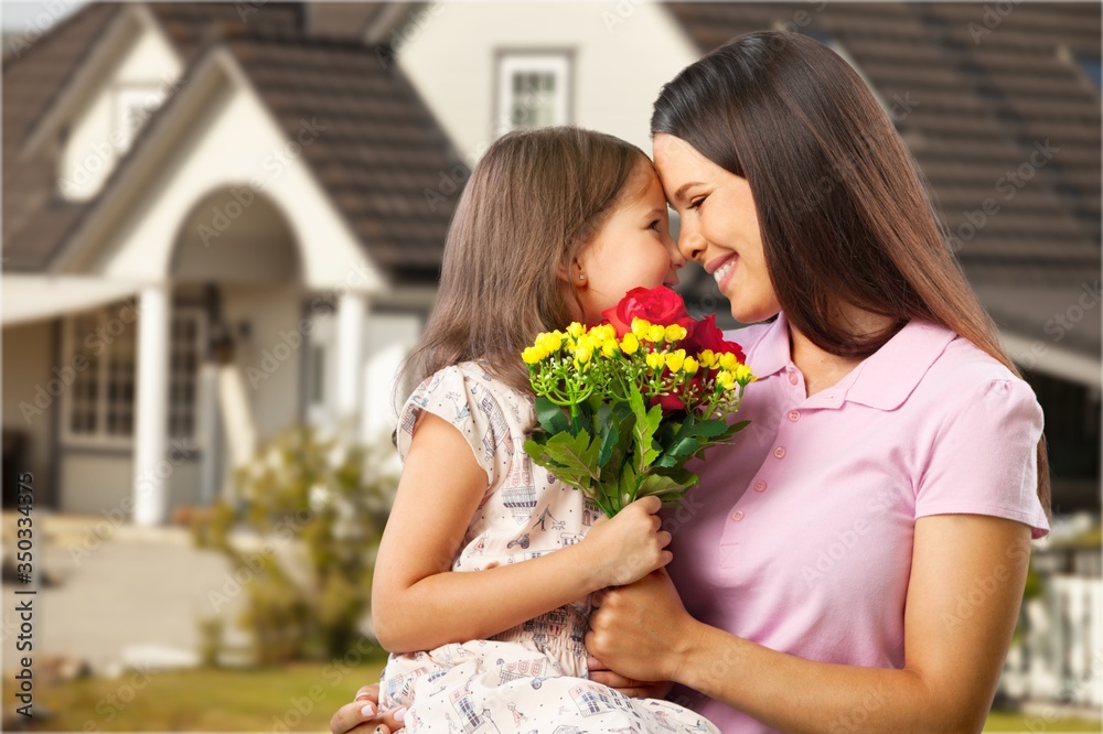Mother and daughter with a bouquet of flowers on house background.