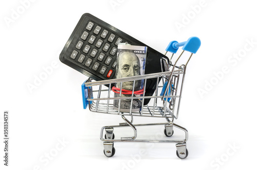 rolled up dollars and a calculator in a shopping cart on a white background. Side view.