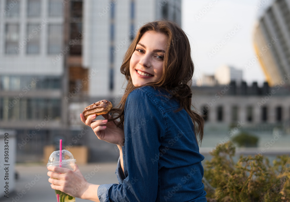 Fototapeta premium young beautiful woman is enjoying with cake and drink on city street