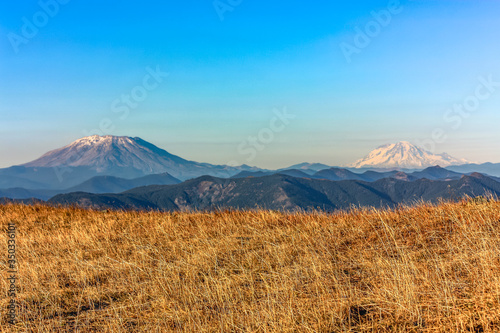 Mt St Helen and Mt Adam at near sunset overlooking a field of grass and rolling hills