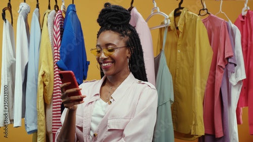 Young cheerful fashion influencer woman vlogger making a live stream video haul conference with followers showing fashion outfit stylish clothes isolated on background.