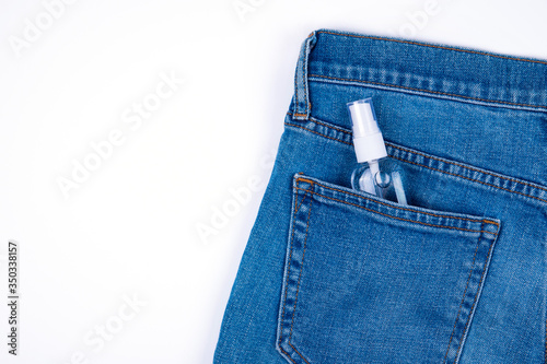 Top view of antibacterial antiseptic spray for hands sanitizer in bottle in jeans pocket isolated on white background with copy space. Prevention against virus, bacteria or coronavirus .