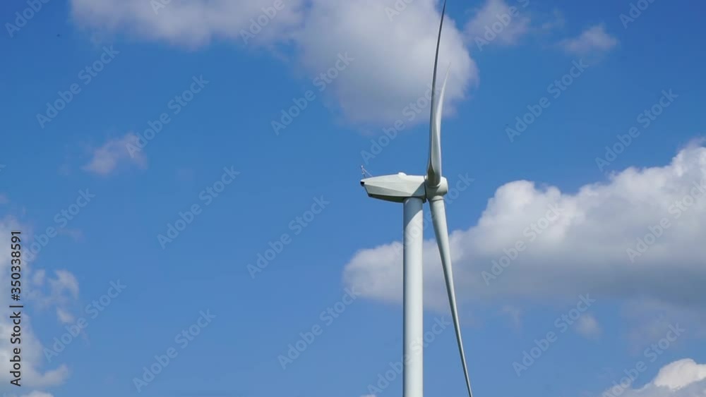 Wind Turbine in Side View with Bright Blue Cloudy Sky Background Wind Turbine in Side View with Bright Blue Cloudy Sky Background