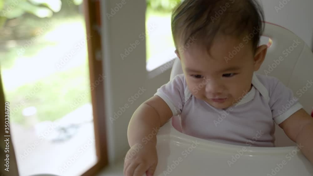 happy asian baby feeding time sitting on highchair happy asian baby feeding time sitting on highchair