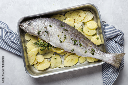 Fresh raw sea bass fish prepared for roasting with potatoes photo