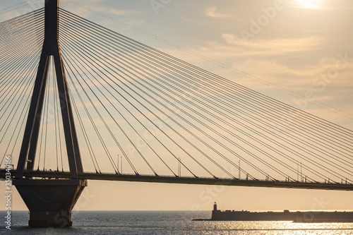 The famous cable bridge Charilaos Trikoupis in Rio Antirio Greece against a warm orange sky during sunset