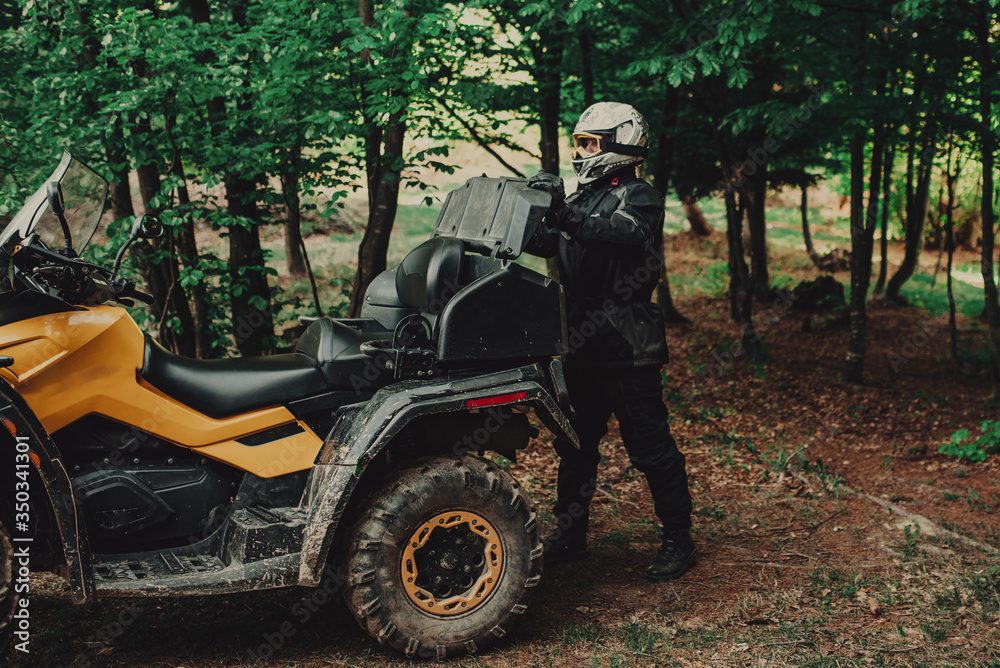 Man preparing his quad for extreme ride in forest