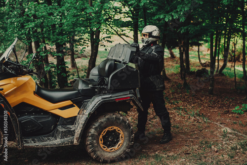 Man preparing his quad for extreme ride in forest