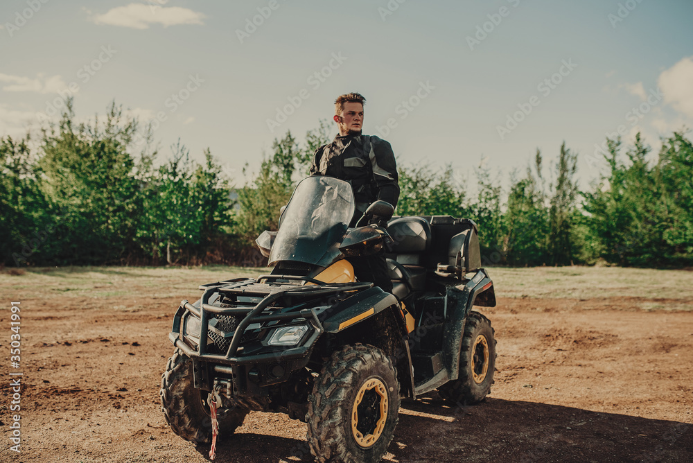 A young man in a white helmet rides through the woods on a Quad bike. Extreme hobby. A trip to ATV on the road from logs. Quad Biking through the forest. A young man in a white helmet rides through the woods on a Quad bike. Extreme hobby. A trip to ATV on the road from logs. Quad Biking through the forest.