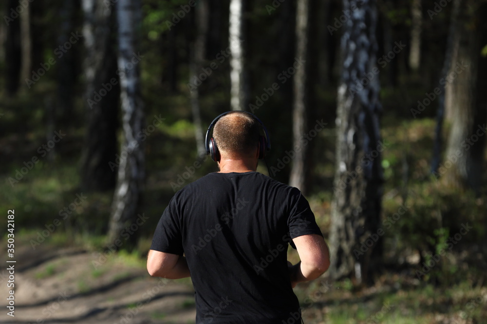 young man jogging in forest, man with headphones on