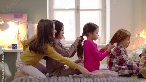 Group of small girl friends on kids sleepover slumber party, plaiting hair.