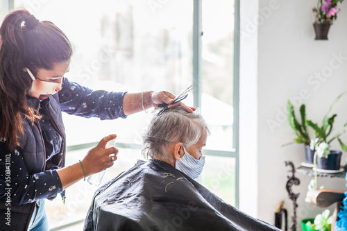 Принти на полотні Senior woman getting a haircut at home during Covid-19 pandemic wearing face mas