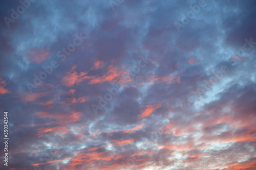 Blue red sunset sky with illuminated clouds