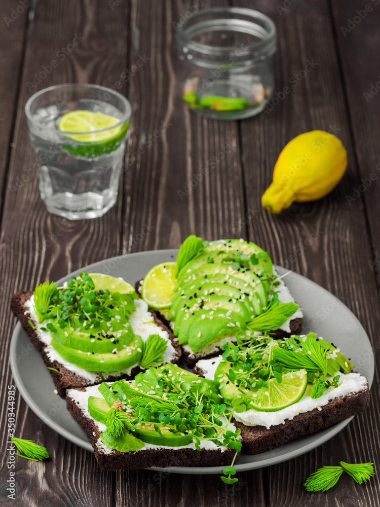 Sandwich with microgreens, cheese, avocado and spruce tips. Close-up, delicious and healthy vegetarian breakfast. Sandwich with microgreens, cheese, avocado and spruce tips. Close-up, delicious and healthy vegetarian breakfast.