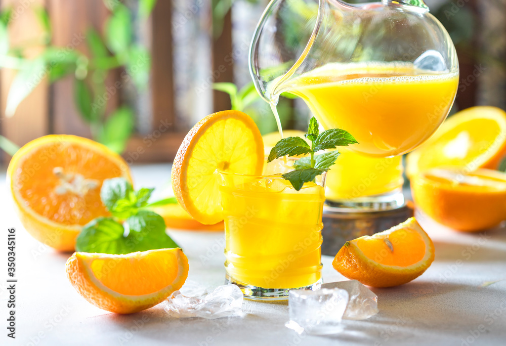 Fresh orange juice, orange slices, mint leaves and ice on a wooden table. Fresh orange juice, orange slices, mint leaves and ice on a wooden table.