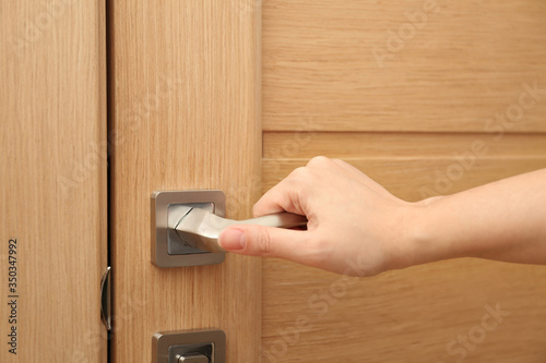 Woman opening door indoors, closeup of hand