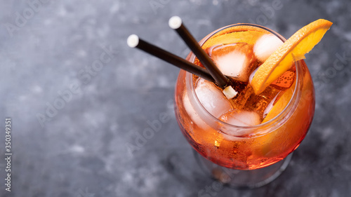 Classic italian aperitif aperol spritz cocktail in glass with ice cubes and with slice of orange on dark background, traditional summer fresh drink, close up and top view, web banner photo