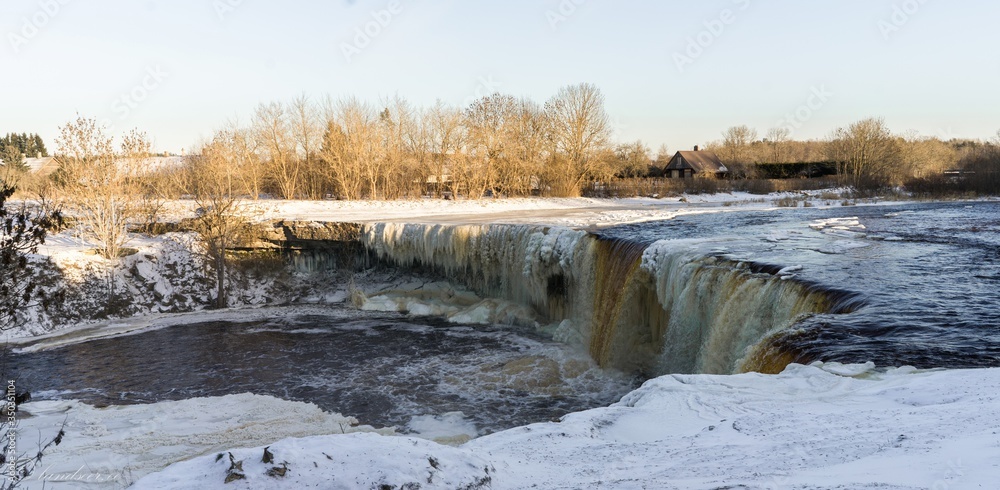 Frozen Jagala waterfall, ice curtain and sculptures. 8 m high and over 50 m wide fall. Winter landscape. Ice curtains from frost. Popular walking area. Lower course of Jägala River . Estonia Frozen Jagala waterfall, ice curtain and sculptures. 8 m high and over 50 m wide fall. Winter landscape. Ice curtains from frost. Popular walking area. Lower course of Jägala River . Estonia