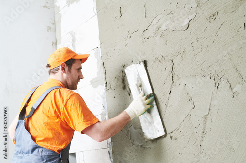 Renovation at home. Plasterer smoothing plaster on wall. photo