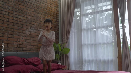 little girl jumping on the bed by herself