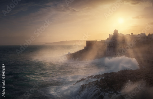 Santa Cesarea Terme in provincia di Lecce al tramonto dopo una mareggiata forte tempesta con mare agitato e onde alte raggi sole photo