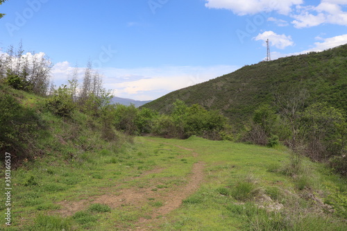 Dirt road in the mountains. Walking along the path is very interesting. You can see the horizon, hills, mountain and clouds. And also spring weather