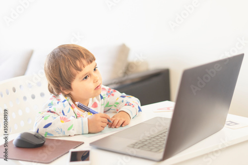 Kid learns at the computer on-line. Child girl learning at home. Home Education Concept