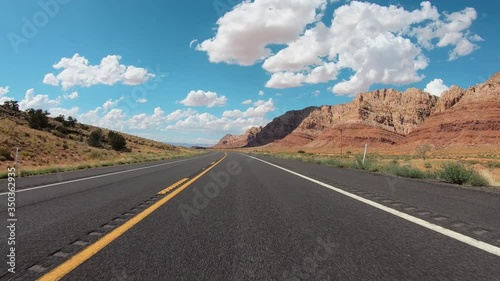 POV Hyperlapse Driving a car on asphalt Arizona desert road with mountains near Grand Canyon. Clear sky with puffy white clouds photo