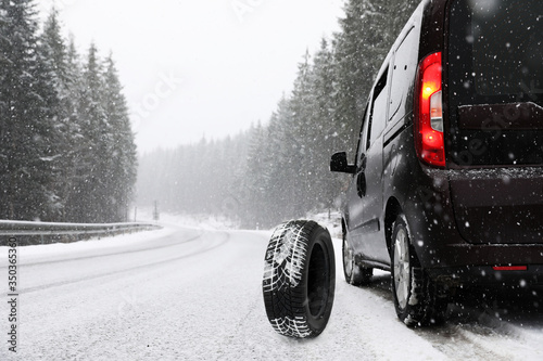 Snow tire near car on road in winter