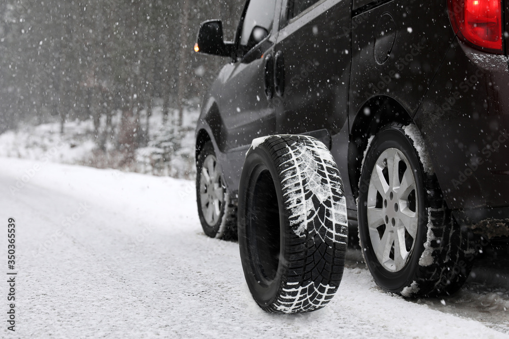 Naklejka premium Snow tire near car on road in winter