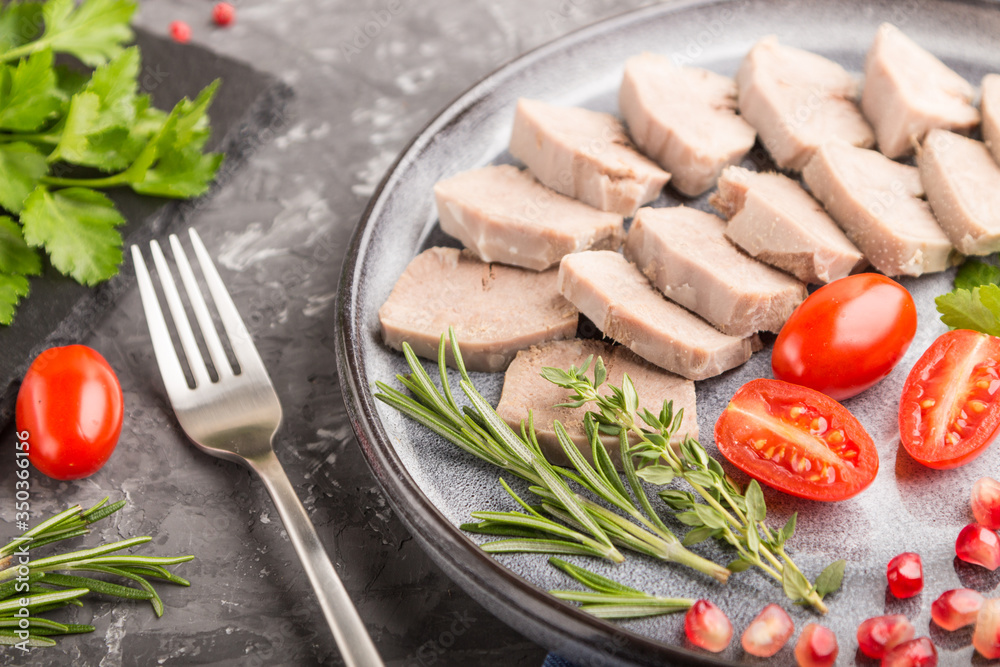 Boiled pork tongue with tomatoes and herbs on a black concrete background. side view, selective focus. Boiled pork tongue with tomatoes and herbs on a black concrete background. side view, selective focus.