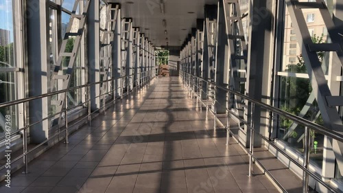 Walking on an empty long iron foot bridge. Way through a long corridor. Walking along an empty tunnel