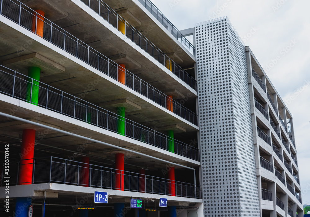 Building with concrete floors and colored support columns. Multi-level parking for cars.