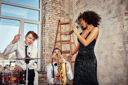 Repetition of multi ethnic jazz band in loft. Female African solist, saxophonist and drummer at loft. Jazz music and jam session concept. passion for music and youth culture concepts photo