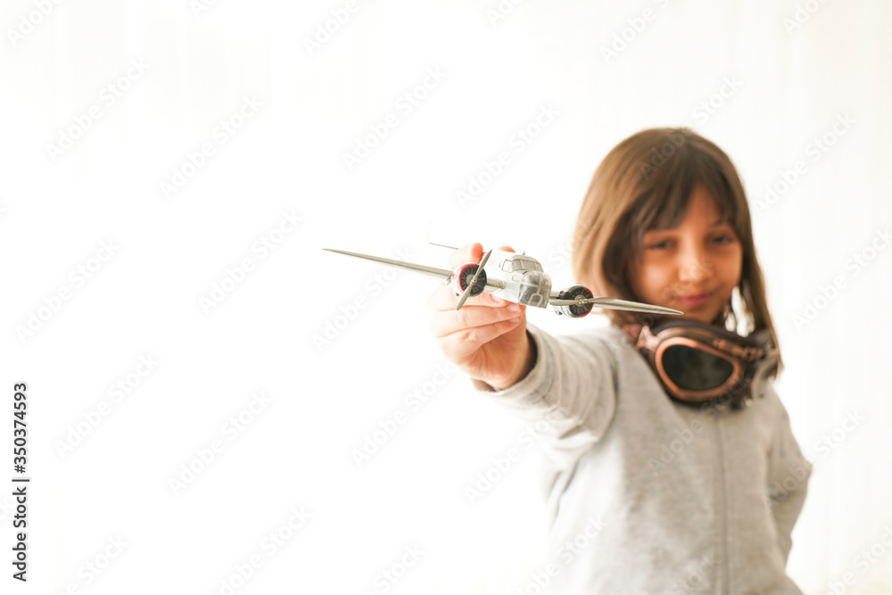 concept of dreams and travels. pilot aviator child with a toy airplane plays at home in his room concept of dreams and travels. pilot aviator child with a toy airplane plays at home in his room