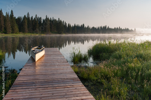 Canoe on a dock at a lake during a misty sunrise. photo