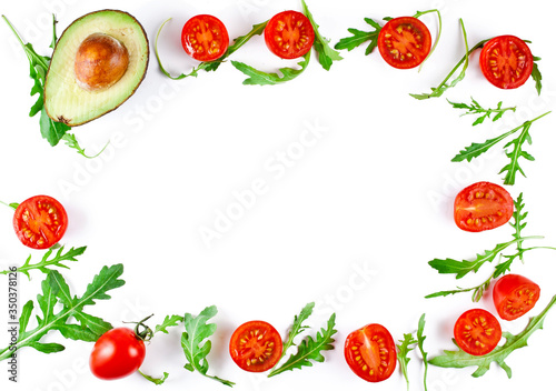 Fototapeta Naklejka Na Ścianę i Meble -  Frame made of halved cherry tomatoes with avocado and rucola leaves isolated on a white background. Copy space. Top view.
