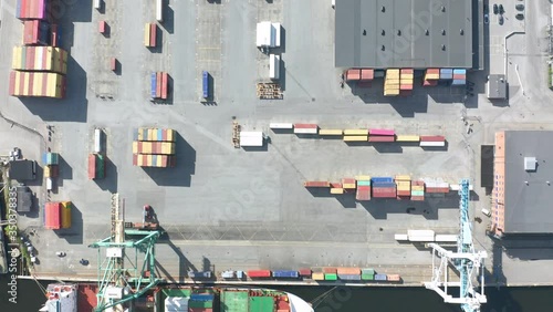 Aerial view of cargo ship moored to container terminal port, tilt down view photo