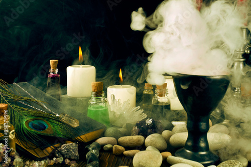 Magic potions  crystals  book  stones  peacock feather  and candles with smoke on a black background.