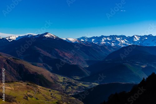 A picturesque wide landscape view of the high snow capped Pyrenees mountain range on a sunny winter day (Hautes-Pyrenees, France)