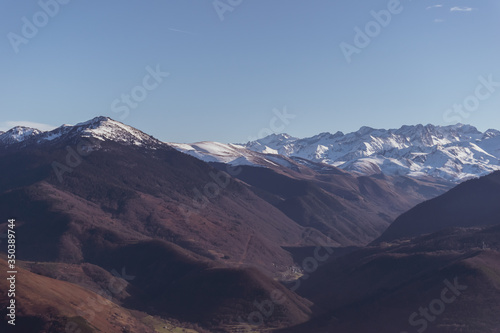 A picturesque wide landscape view of the high snow capped Pyrenees mountain range on a sunny winter day (Hautes-Pyrenees, France)