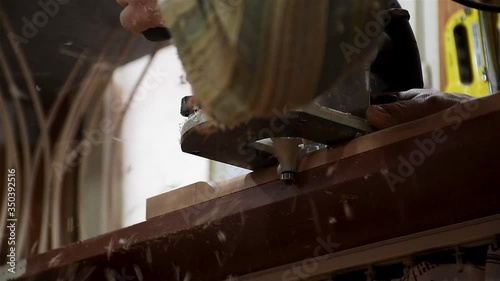 a male woodworker / carpenter, hands only routing edge of the wooden piece with hand router in workshop photo