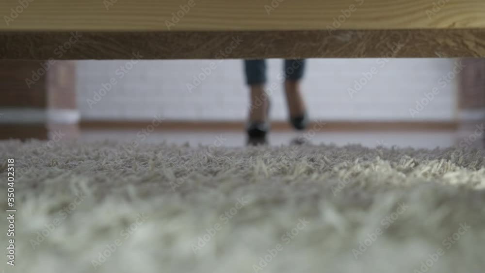 Take off high heels after work. The view from under the bed of a woman in heels taking off her shoes. Take off high heels after work. The view from under the bed of a woman in heels taking off her shoes.